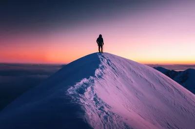 Mountaineer Standing On A Snowy Mountain Peak At Sunrise
