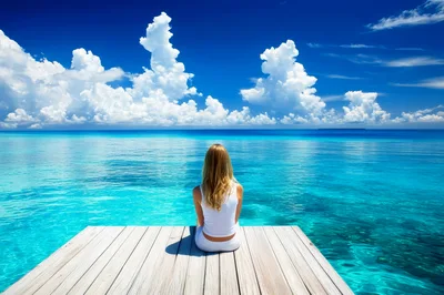 Woman Sitting On A Wooden Pier Overlooking Tropical Ocean