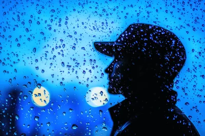 Silhouette Of A Man Looking Through A Rainy Window