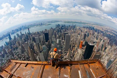 Construction Worker Standing On High Rise Building Rooftop