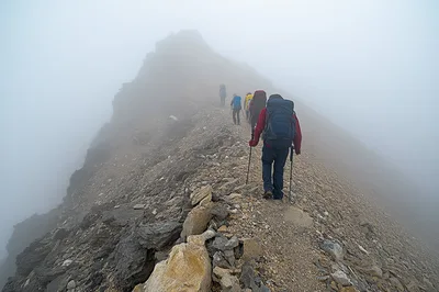 Group Of Hikers Trekking Along A Foggy Mountain Ridge