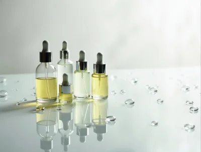 Glass Dropper Bottles With Yellow Serum On Reflective Surface