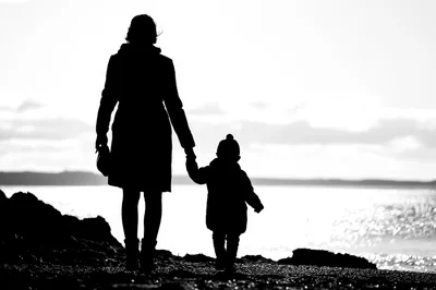 Silhouette Of A Mother And Child Walking By Water