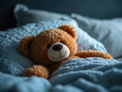 Brown Teddy Bear Sleeping Under A Blue Blanket