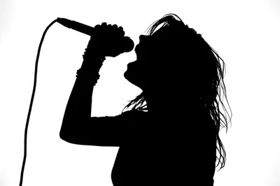 Silhouette Of A Female Singer Performing With A Microphone