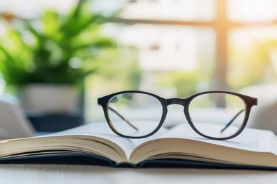Black Rimmed Glasses Resting On An Open Book