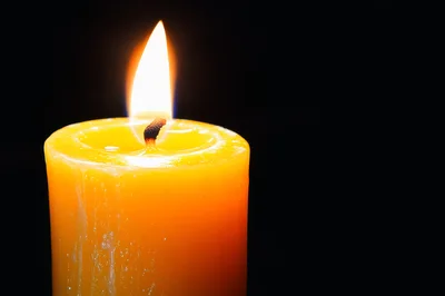 Burning Yellow Candle Against A Black Background