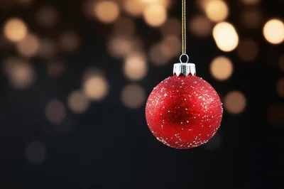 Red Glitter Christmas Ornament Hanging Against Bokeh Background