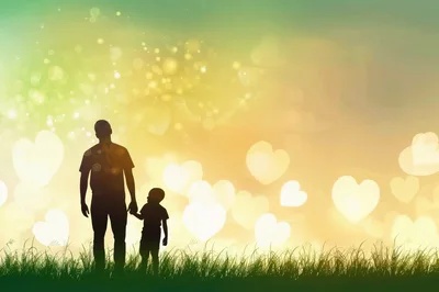 Silhouette of Father and Son Holding Hands in Meadow