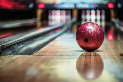 Red Bowling Ball Resting On A Polished Wooden Lane