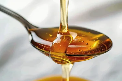 Golden Honey Pouring From A Metal Spoon