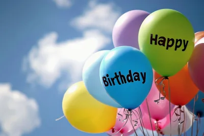 Colorful Happy Birthday Balloons Floating Against Blue Sky