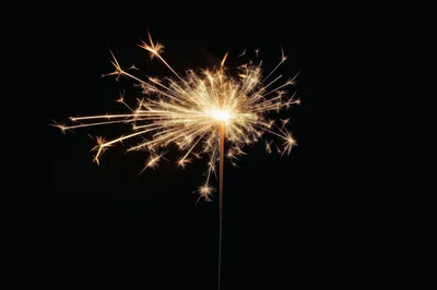 Bright Burning Sparkler Against A Solid Black Background