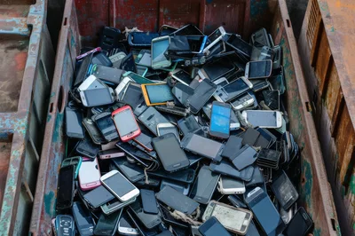 Pile Of Discarded Old Mobile Phones In Metal Bin