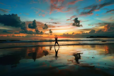 Woman Practicing Yoga Pose on Beach at Sunset
