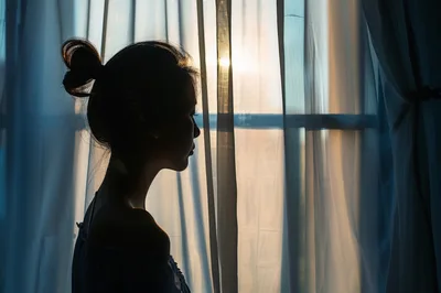 Silhouette Of A Woman Standing By A Window