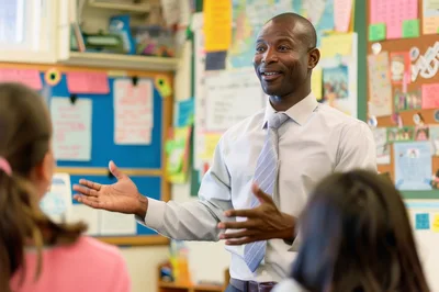 African American Male Teacher Instructing Students In Classroom