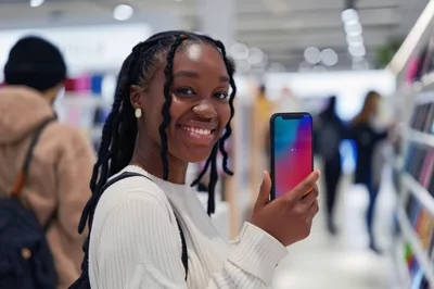 Young Woman Holding Smartphone In A Retail Store