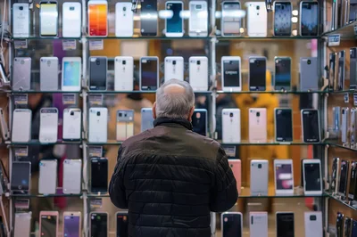 Senior Man Browsing Smartphones In Electronics Store
