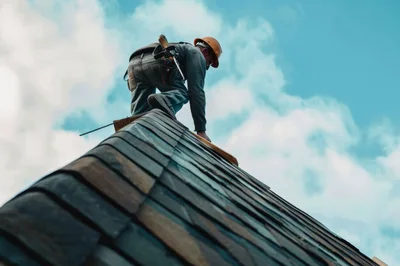 Construction Worker Installing Shingles On A Roof