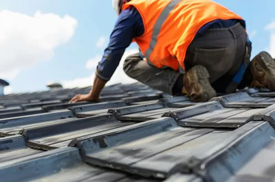 Construction Worker Installing Roof Tiles On Residential House