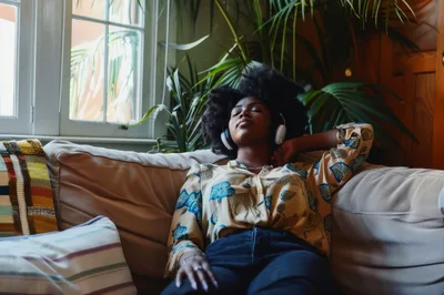 Young Black Woman Relaxing On Sofa Listening To Music