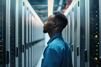 African American IT Technician Inspecting Server Room Racks