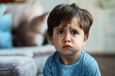 Sad Toddler Looking At Camera In Living Room