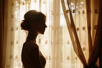 Silhouette Of A Bride Standing By A Window