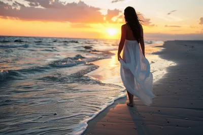 Woman Walking Along Beach At Sunset