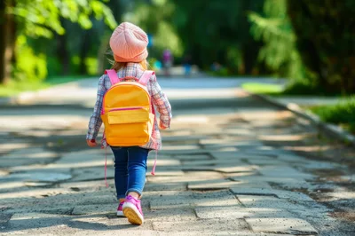 Little Girl Walking Down A Park Path With Backpack