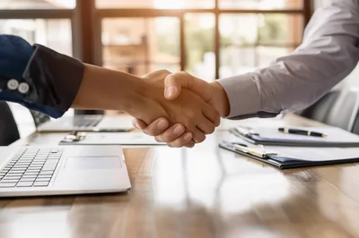 Business Professionals Shaking Hands Over Office Desk