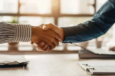 Business Professionals Shaking Hands Over Office Desk