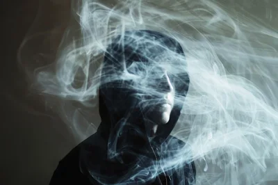 Man Wearing Hood Surrounded By Swirling White Smoke