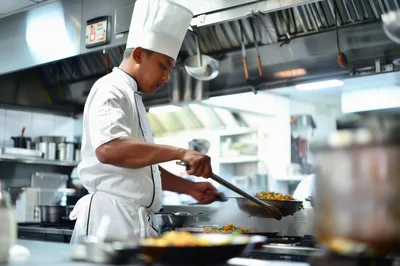 Professional Chef Cooking Stir Fry in Commercial Kitchen