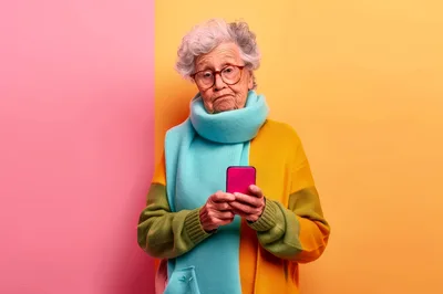 Elderly Woman Using A Smartphone Against A Colorful Background