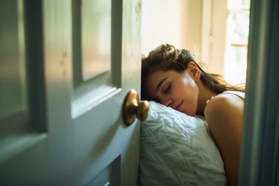 Young Woman Sleeping Peacefully Against A Door