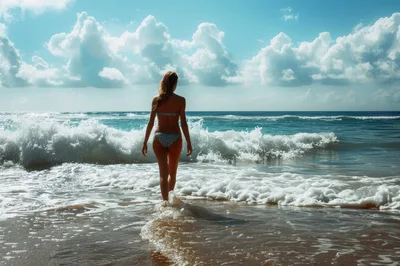 Woman Walking Into Ocean Waves On Sunny Beach