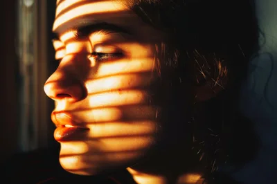 Young Woman With Blinds Shadow Pattern On Face