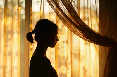 Silhouette Of A Young Woman Standing By A Window