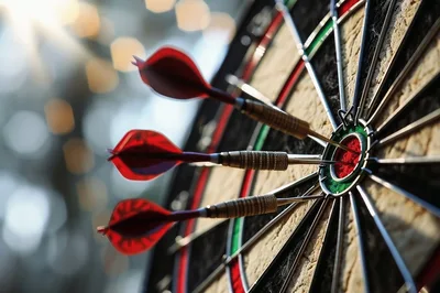 Three Darts Hitting The Bullseye On A Dartboard