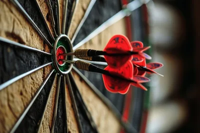 Three Darts Hitting The Bullseye On A Dartboard