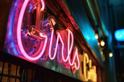 Neon Girls Sign Glowing In Nighttime City Street