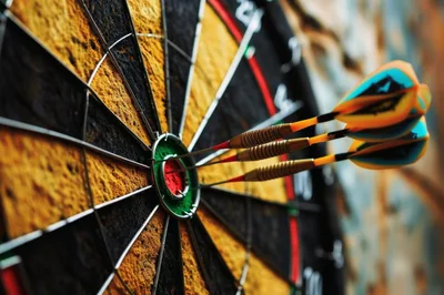 Three Darts Hitting The Bullseye On A Dartboard