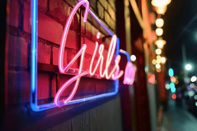 Neon Girls Sign On A Brick Wall At Night