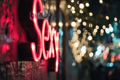 Neon Sexy Sign Glowing on Brick Wall at Night