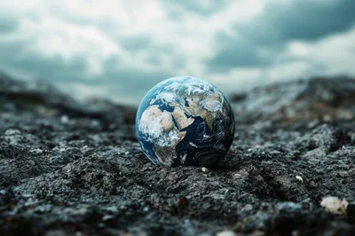 Miniature Earth Globe Resting On Barren Rocky Ground