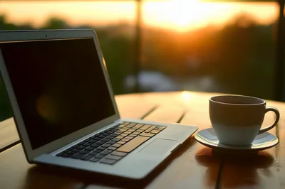 Laptop And Coffee Cup On Outdoor Table At Sunset