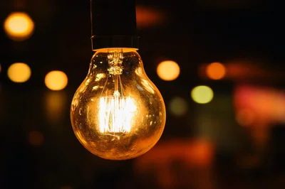 Glowing Vintage Edison Light Bulb Hanging In Dark Room
