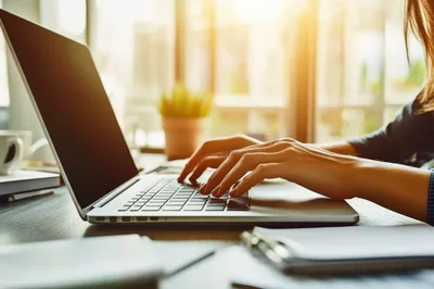 Woman Typing On Laptop In Sunny Office